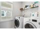 Well-organized laundry room with white washer and dryer, shelving and a window at 117 Osprey Ridge Ln, Summerville, SC 29483