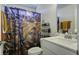 Bathroom with a patterned shower curtain, a white sink, a mirror, and storage shelves at 1209 Hammrick Ln, Johns Island, SC 29455