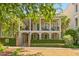 Elegant two-story home featuring a spacious double porch with white pillars, surrounded by lush greenery at 121 W Shipyard Rd, Mount Pleasant, SC 29464