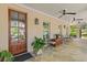Cozy covered porch featuring tile flooring, comfortable seating, ceiling fans and a wooden front door at 121 W Shipyard Rd, Mount Pleasant, SC 29464
