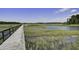 Picturesque view of a long wooden boardwalk stretching across a marsh, leading to a tranquil coastal community at 148 Cowrie Ct, Mount Pleasant, SC 29464