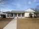 Charming single-story home featuring a covered porch with classic columns, a modern metal roof and well-manicured lawn at 148 Cowrie Ct, Mount Pleasant, SC 29464