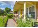 Eye-level view of sunny front porch with rocking chairs and yellow door, with lush landscaping at 1575 Langston Dr, Johns Island, SC 29455