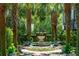 Picturesque courtyard with a stone fountain, surrounded by manicured palm trees and decorative potted plants at 172 Tradd St, Charleston, SC 29401