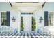 Welcoming front porch with checkered flooring, elegant benches, and gas lanterns flanking the front door at 172 Tradd St, Charleston, SC 29401