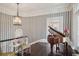Cozy living area featuring dark hardwood floors, striped wallpaper, and a beautiful grand piano at 172 Tradd St, Charleston, SC 29401