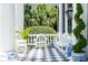 Inviting porch with black and white checkered floors, white chairs, and elegant potted plants at 172 Tradd St, Charleston, SC 29401
