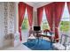 Cozy sitting area with floral wallpaper, large windows with red drapes, and striped rug at 172 Tradd St, Charleston, SC 29401