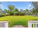 Well-manicured backyard features a lush green lawn, mature trees, and black wrought iron fence at 2017 Woodland Shores Rd, Charleston, SC 29412