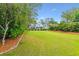 Expansive backyard with lush green lawn, mature trees, and black wrought iron fence at 2017 Woodland Shores Rd, Charleston, SC 29412