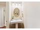 Bright powder room with pedestal sink, framed artwork, and a round mirror at 2017 Woodland Shores Rd, Charleston, SC 29412