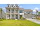 Two-story home with double porches, attached garage, manicured lawn and colorful flowerbeds at 3173 Hugh Bennett Dr, Johns Island, SC 29455