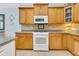 Bright kitchen with wooden cabinets, tile backsplash, and modern white appliances for cooking convenience at 318 Oyster Bay Dr, Summerville, SC 29486