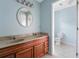 Bathroom featuring a dual sink vanity, bright lighting, a round mirror and a toilet within a cleanly tiled space at 33 Elliott Ct, Walterboro, SC 29488