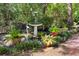 Serene backyard featuring a bird bath, lush greenery, and potted ferns on a brick patio, creating a peaceful retreat at 344 Lantana Dr, Charleston, SC 29407
