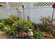 Charming backyard garden featuring a white picket fence, various sculptures, and vibrant flowering plants at 344 Lantana Dr, Charleston, SC 29407