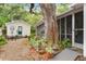 Secluded backyard with brick patio, mature trees, lush landscaping, and a guest house at 344 Lantana Dr, Charleston, SC 29407