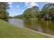 View of the lake with grass on the edge and a shoreline of sand, surrounded by lush trees at 4292 Cloudmont Dr, Hollywood, SC 29449