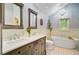 A luxurious bathroom featuring double vanity, soaking tub, elegant chandelier, and patterned tile flooring at 4292 Cloudmont Dr, Hollywood, SC 29449