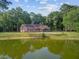 Backyard of a charming property with a swimming pool that reflects the trees surrounding it and the calming pond at 4292 Cloudmont Dr, Hollywood, SC 29449