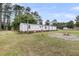 View of the backyard with trees, lush green grass, a firepit, and a shed at 5056 Red Oak Rd, Cottageville, SC 29435