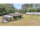 View of a barn on property surrounded by tall trees and with mobile home in the background and some foliage at 5056 Red Oak Rd, Cottageville, SC 29435