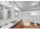 Bathroom with dual sinks, corner tub, toilet, wood-look flooring, and a window at 5056 Red Oak Rd, Cottageville, SC 29435