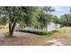 Single-story home with mature trees, well-kept hedges and a wooden front porch at 5056 Red Oak Rd, Cottageville, SC 29435