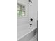 This bathroom features a white bathtub, marble walls, and black hardware, creating a modern and elegant bathing space at 5774 Scott White Rd, Hollywood, SC 29449