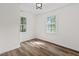 Bright bedroom with hardwood floors, white walls, and natural light streaming through two windows, creating a serene atmosphere at 5774 Scott White Rd, Hollywood, SC 29449