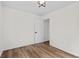 Bright, minimalist bedroom featuring hardwood floors, white walls, modern light fixture, and a door leading to another room at 5774 Scott White Rd, Hollywood, SC 29449