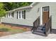 Close up view of a home featuring a light green exterior, gray stairs, brown door and dark trim at 5774 Scott White Rd, Hollywood, SC 29449