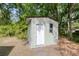 Utility shed with light green siding and a white door nestled among the trees in the back of the property at 5774 Scott White Rd, Hollywood, SC 29449