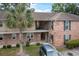 Two-story brick exterior of a building featuring an entryway, balconies, and a well-manicured lawn with a palm tree at 6240 Old Point Rd # C-8, Hanahan, SC 29410