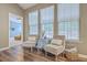 Sunlit sitting area featuring two upholstered chairs with decorative pillows and three large windows at 7690 High Maple Cir, North Charleston, SC 29418