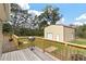 View of a detached, beige colored shed with white door and white roll-up door as seen from wood back deck at 8476 Old Georgetown Rd, McClellanville, SC 29458