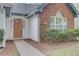 Close-up of a charming home's front entry with a wood door, brick accents, and well-kept landscaping at 8774 Adaline St, North Charleston, SC 29406