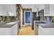 Kitchen view with stainless steel appliances, white cabinets, floral wallpaper, and wood flooring at 8774 Adaline St, North Charleston, SC 29406