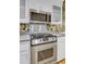 Close-up of a stainless steel stove and microwave surrounded by white cabinets and floral wallpaper at 8774 Adaline St, North Charleston, SC 29406