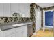 A kitchen sink and countertop featuring white cabinets and floral wallpaper in the background at 8774 Adaline St, North Charleston, SC 29406