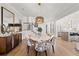 Dining area with a round marble table, patterned chairs, modern lighting fixture, stairs and kitchen in the background at 9822 Haven Loop, Johns Island, SC 29455
