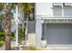 Exterior view of a charming home with a stairway, gray garage door, and a lush palm tree at 9822 Haven Loop, Johns Island, SC 29455