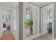 Bright hallway with hardwood floors, French doors to porch, and scenic wallpaper detail creating a stylish transition at 9822 Haven Loop, Johns Island, SC 29455