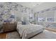 Bright bedroom features patterned wallpaper, hardwood floors, two side tables with lamps and a view to the outside at 9822 Haven Loop, Johns Island, SC 29455