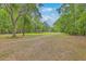 Expansive property showcasing a long driveway, a covered dock, and a glimpse of the charming home surrounded by lush trees at 100 Canal Rd, Saint George, SC 29477