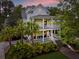 Elegant two-story home with double porches, mature landscaping, and a bench on the porch at 11 Dalton St, Daniel Island, SC 29492