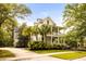 Charming two-story home with double porches, mature palm trees, and a winding driveway at 11 Dalton St, Daniel Island, SC 29492
