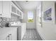 Modern laundry room with black and white patterned tile and white cabinets and appliances at 11 Dalton St, Daniel Island, SC 29492