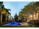 Inviting pool is illuminated at dusk, with a hot tub, lounge chairs, and verdant landscaping at 11 Dalton St, Daniel Island, SC 29492
