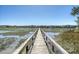 Picturesque wooden dock stretching across the tranquil marsh, leading to serene waters and distant shorelines at 1141 Hills Plantation Dr, Charleston, SC 29412